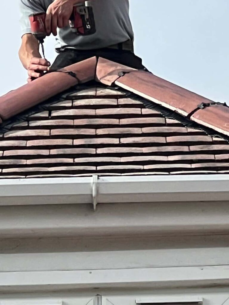 This is a photo of one of the operatives of Arundel Roofing Repairs installing new ridge tiles