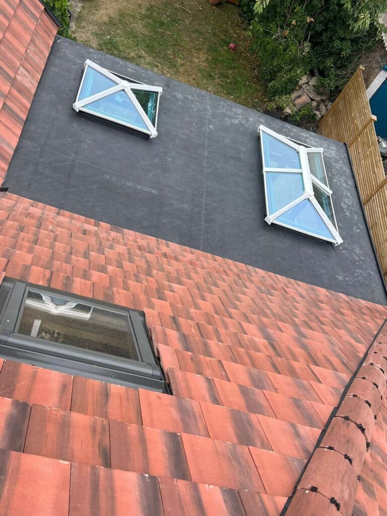 This is a photo taken from the roof ridge looking down a tiled pitched roof on to a flat roof. Works carried out by Arundel Roofing Repairs
